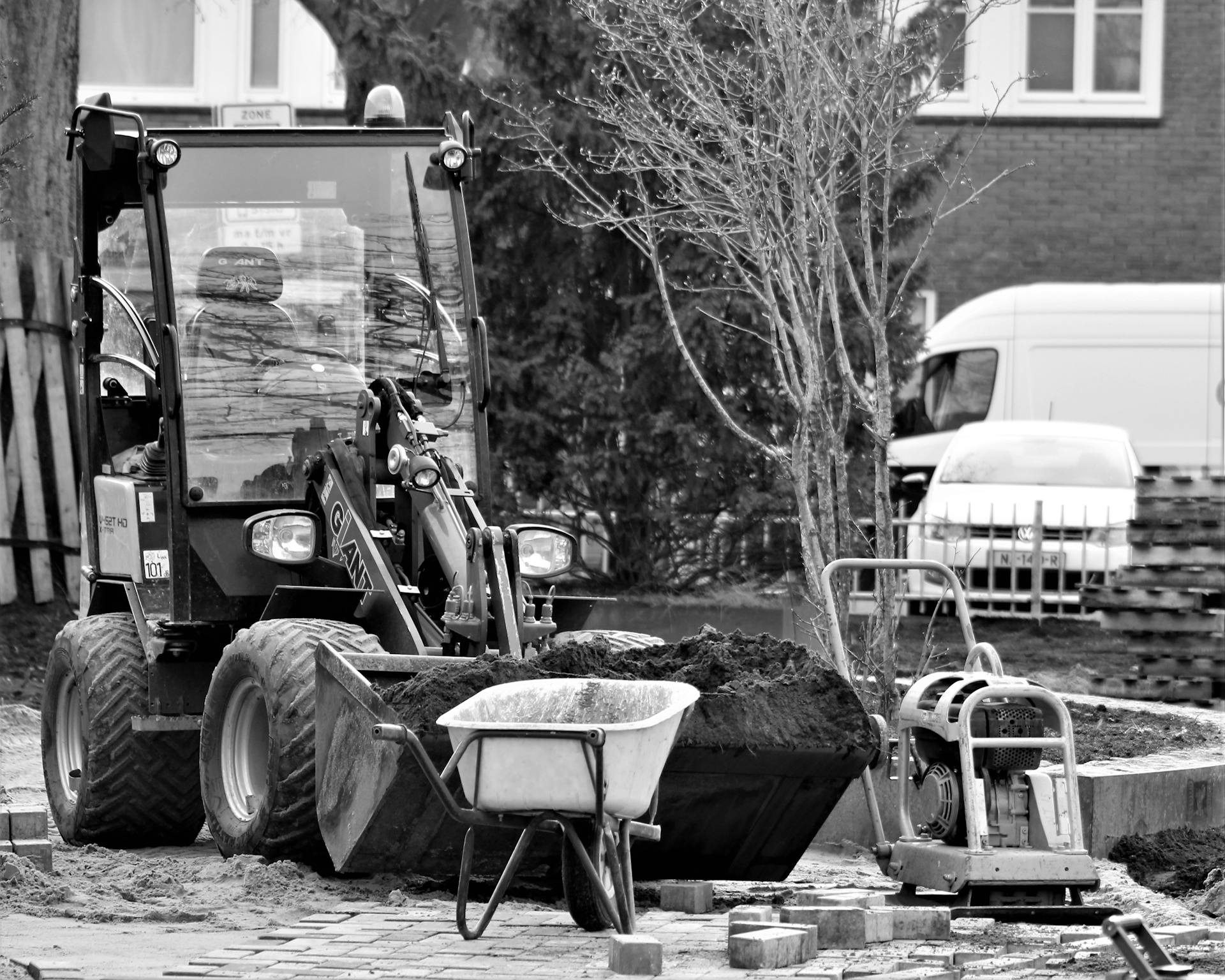 A black and white image showing construction machinery and tools operating outdoors.