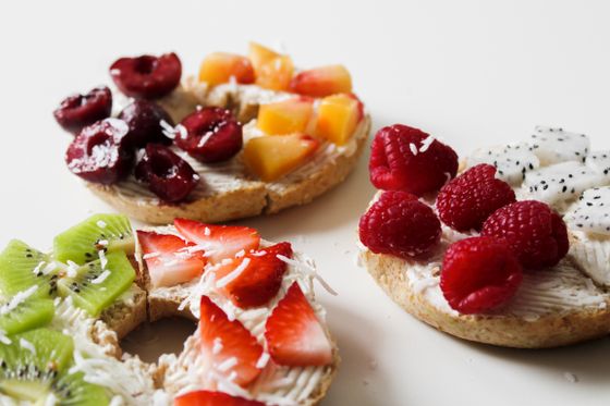 Toasted bagel halves spread with cream cheese, topped with cherries, peaches, raspberries, kiwi and strawberries
