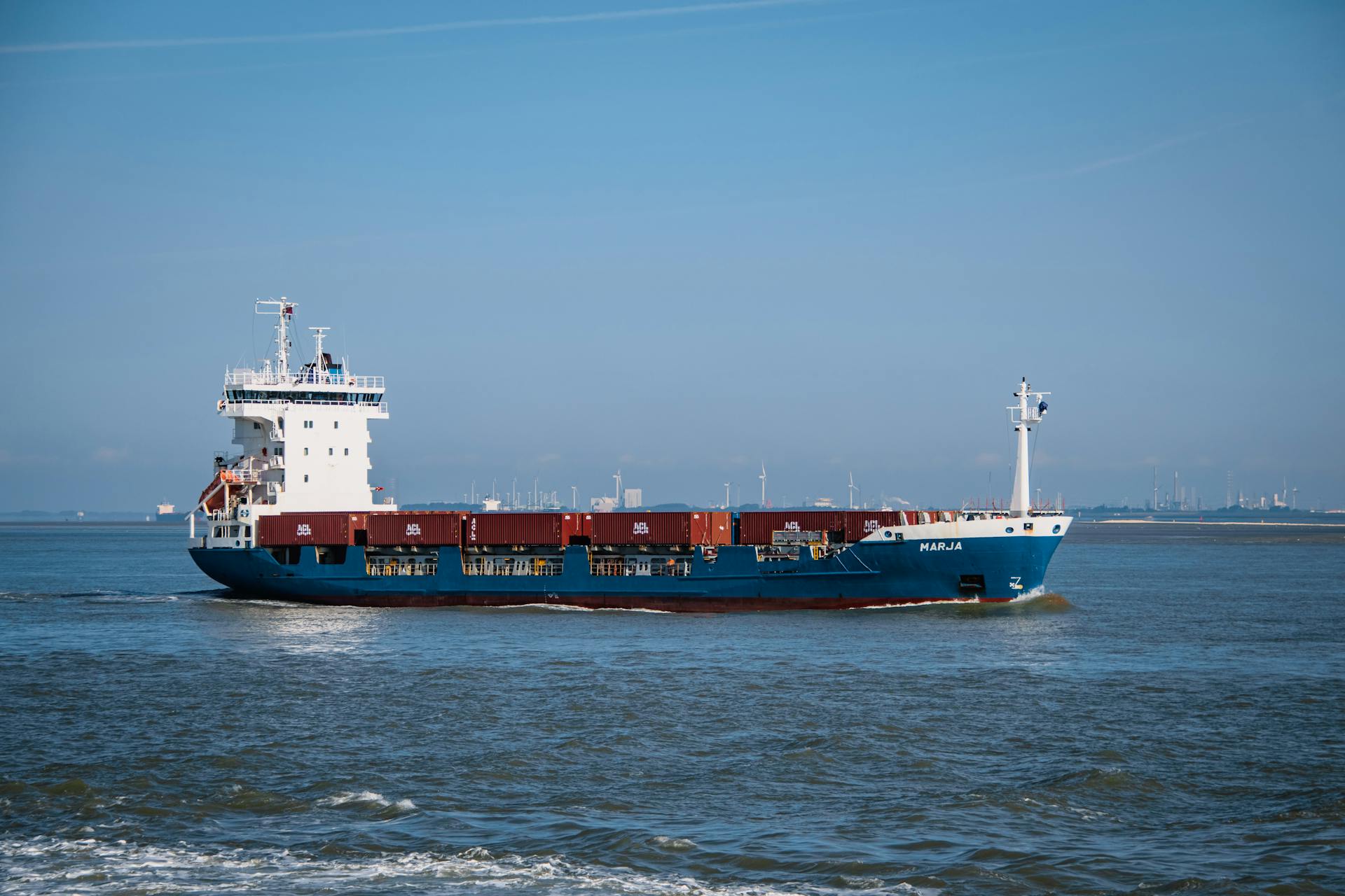 A cargo ship with containers sails in a clear blue sea near Terneuzen, Netherlands.