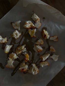A creative display of bread pieces on paper, captured in a dark and moody atmosphere.