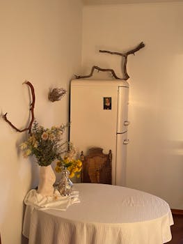 Warmly lit rustic interior with floral display and vintage furniture, exuding charm and comfort.