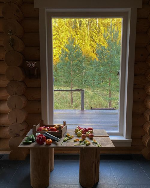 Free Wooden table with fresh vegetables, set against a scenic window view in a rustic cabin. Stock Photo