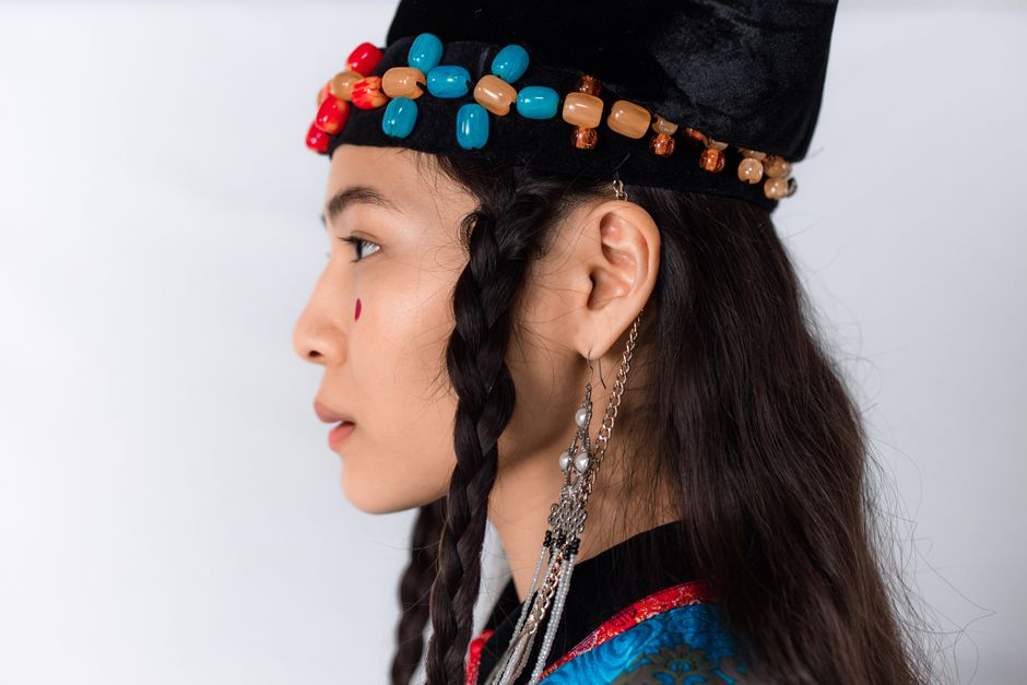 Close-up profile of a woman in traditional Mongolian attire with braided hair.