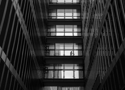 Free Dramatic black and white photo of a modern city skyscraper with silhouetted pedestrian. Stock Photo