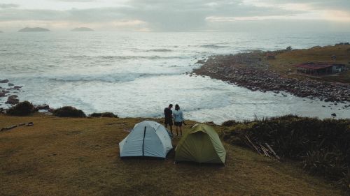 Free Two tents and a couple enjoying a scenic coastal view in Palhoça, Brazil. Stock Photo