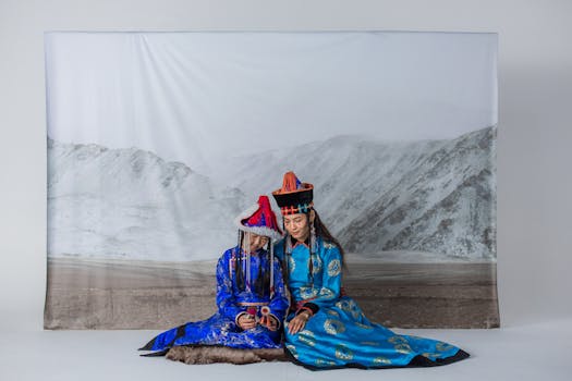 Two women wearing traditional Mongolian clothing and hats in a studio setup.