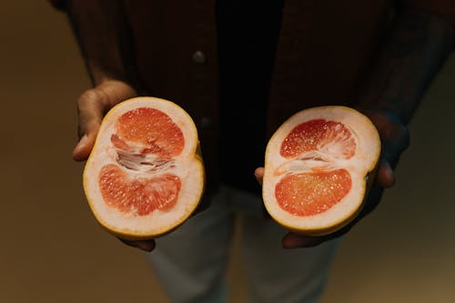 A Person Holding Unpeeled Sliced Pomelo