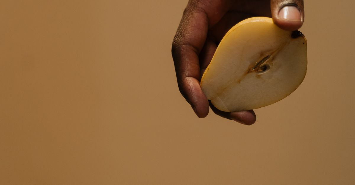 Clean Pear Hand Hand Holding a Sliced Pear · Free Stock Photo