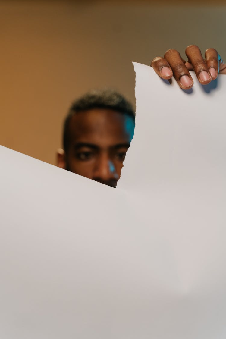 A Man Tearing A Sheet Of Paper