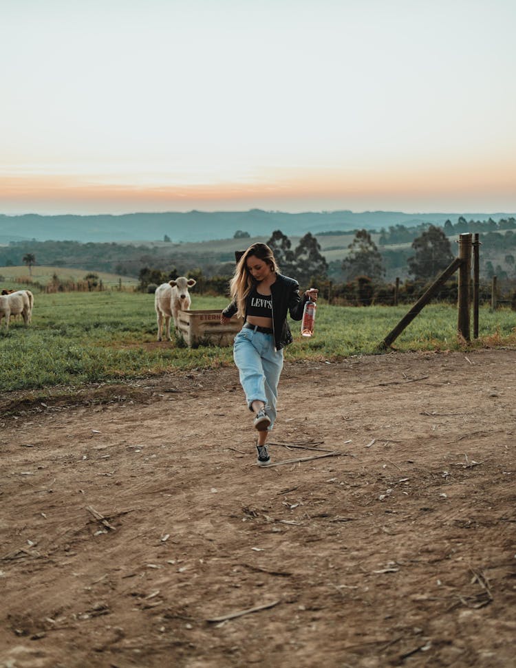 A Woman Hopping While Holding A Bottle Of Liquor