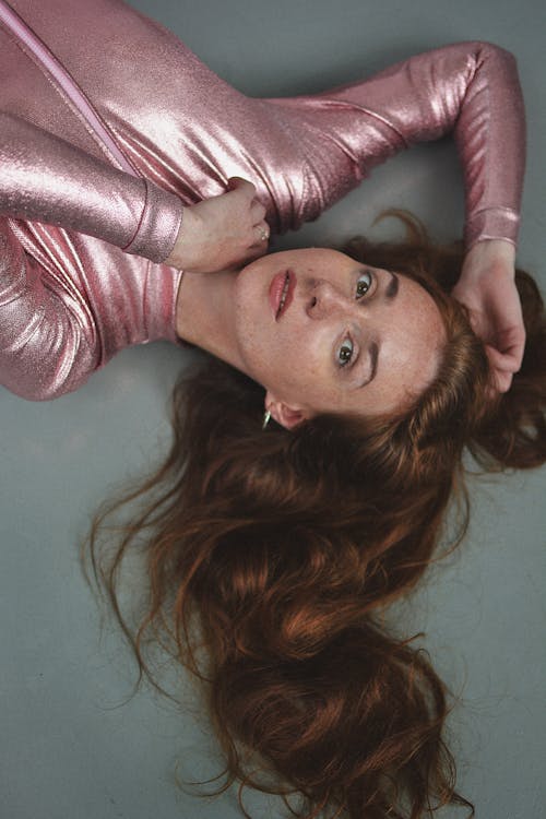 Free A Woman Wearing a Pink Glittery Top Lying on the Floor Stock Photo