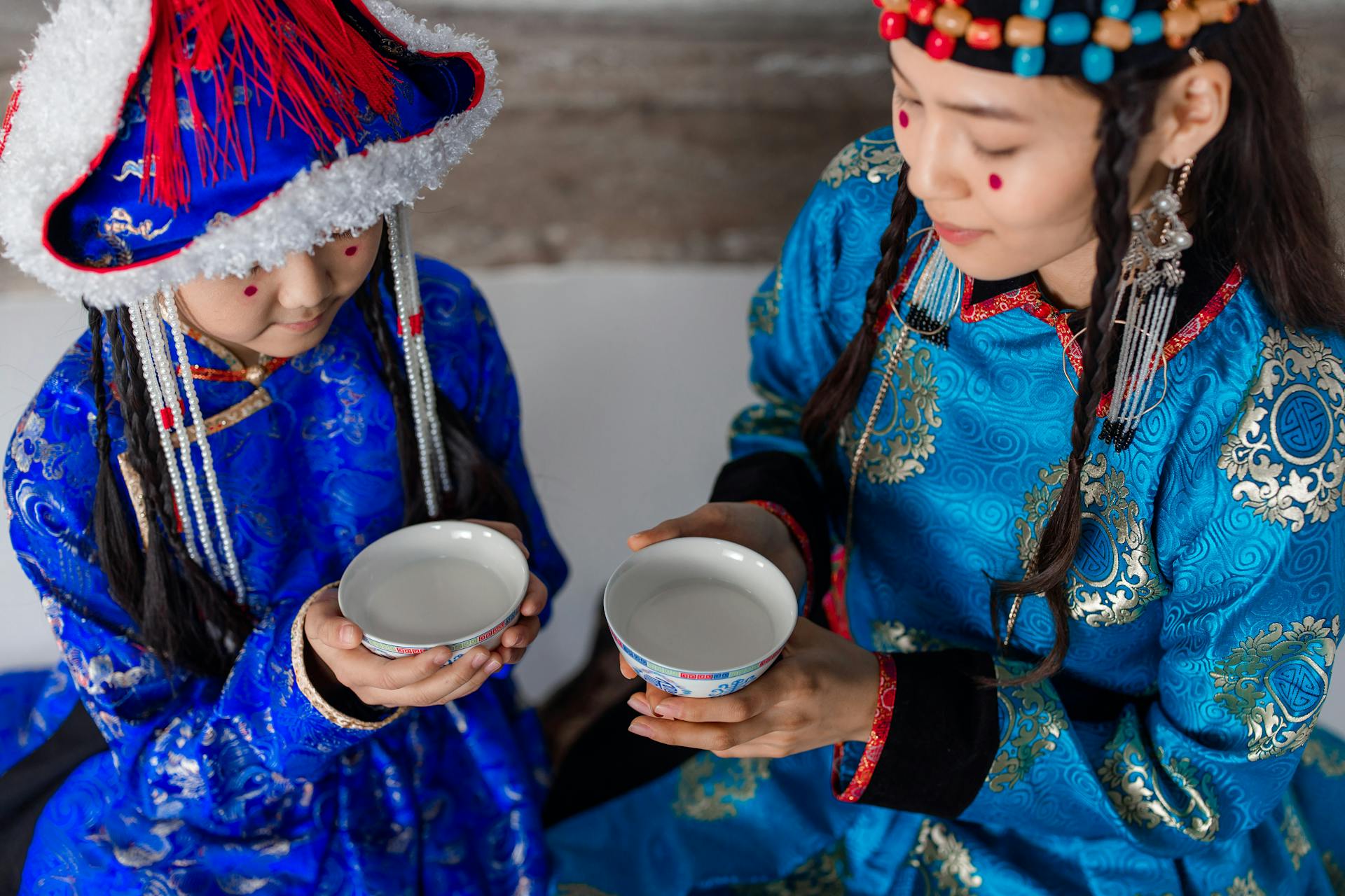 A Woman and a Girl with Red Spots on Cheeks Holding Bowls of Milk