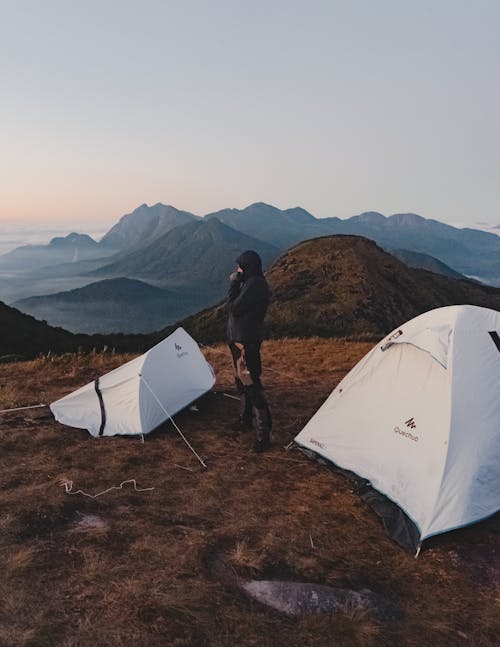 Photo of a Person Standing Beside Between Tents