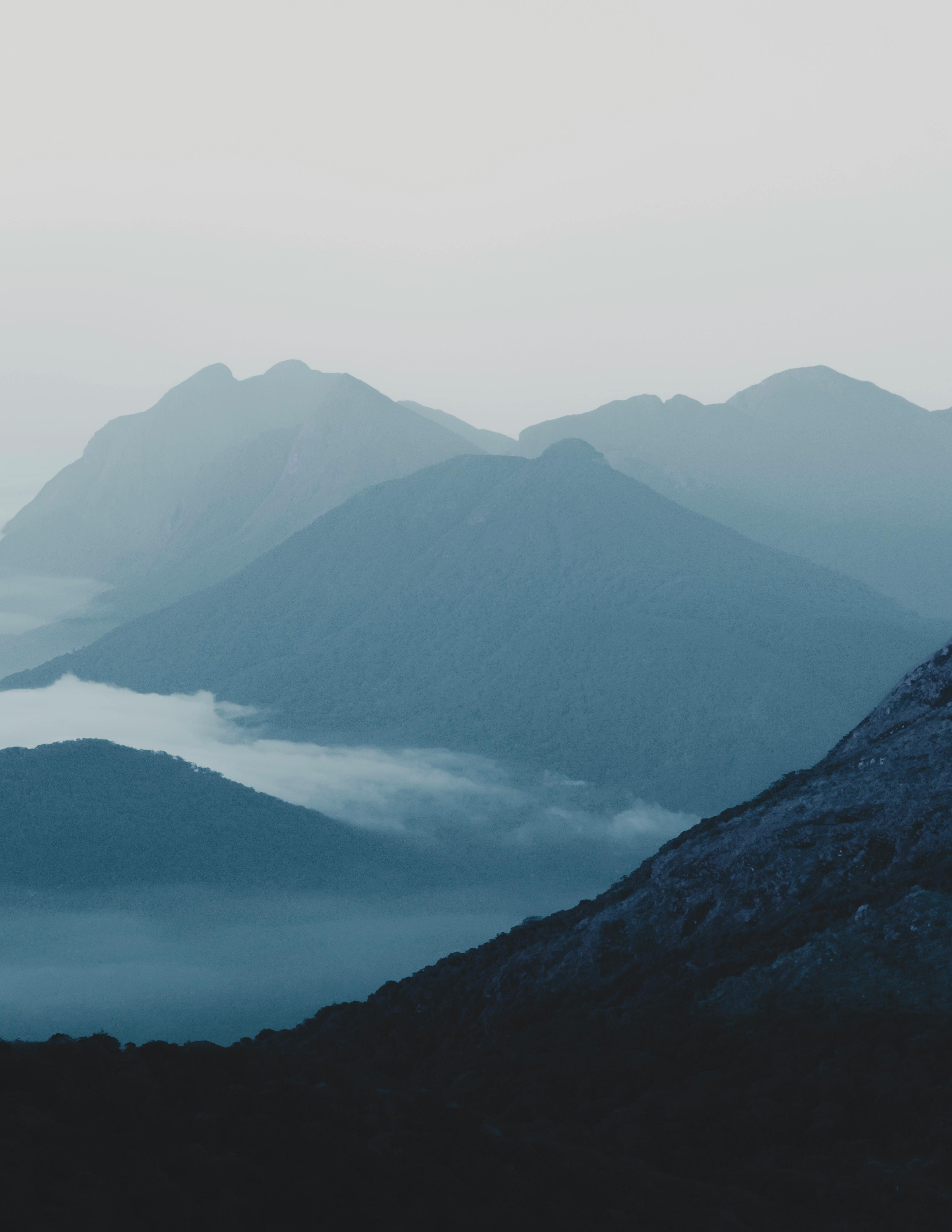 Explore the serene beauty of misty mountain ranges captured in early morning light, enveloped in tranquil fog.
