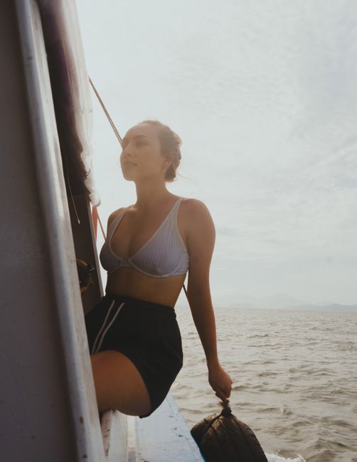 A serene moment of a woman sitting on a yacht edge with the ocean view in the background.