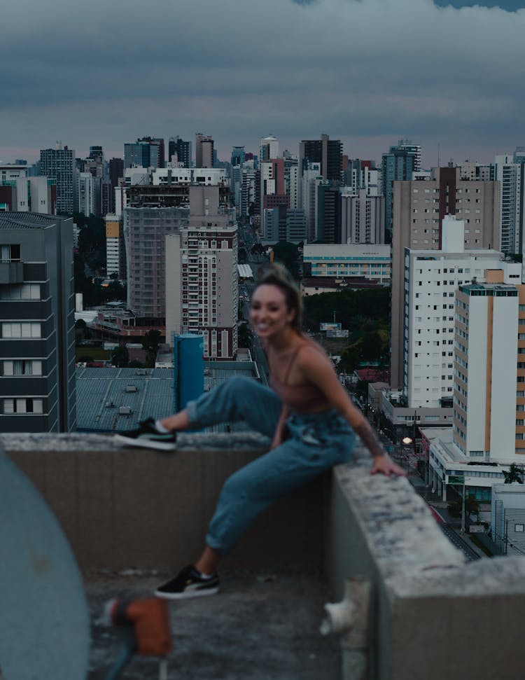 A Woman Sitting At The Edge Of A Rooftop