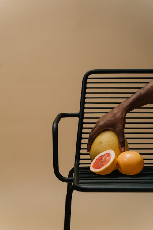 A Person Holding a Pomelo on a Steel Chair