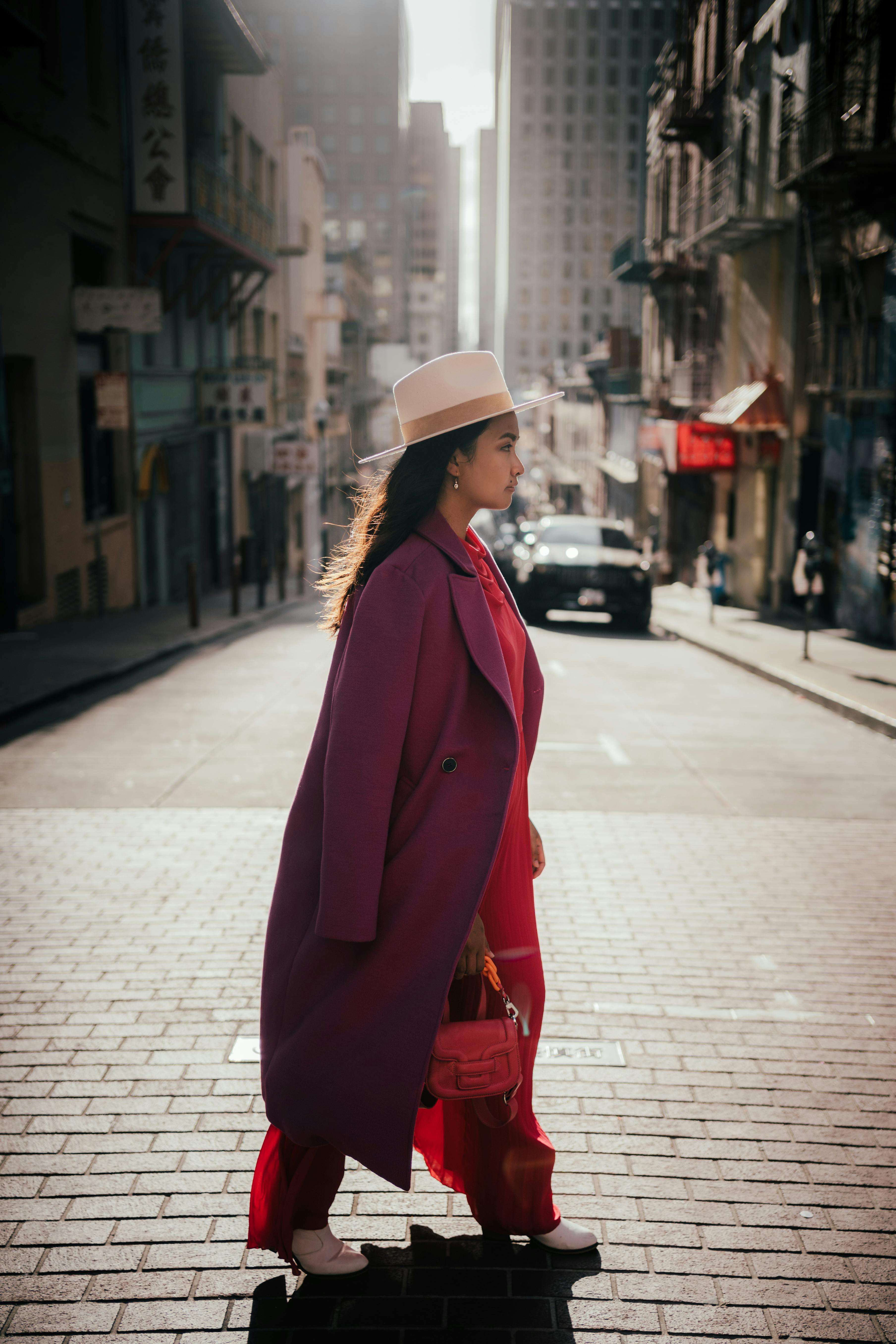 woman in red coat and white knit cap standing on sidewalk