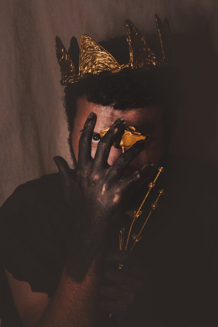 A Man Wearing A Gold Crown With Hands Painted Black