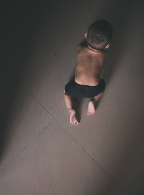 Free Toddler in Black Shorts Crawling on Grey Floor Tiles Stock Photo