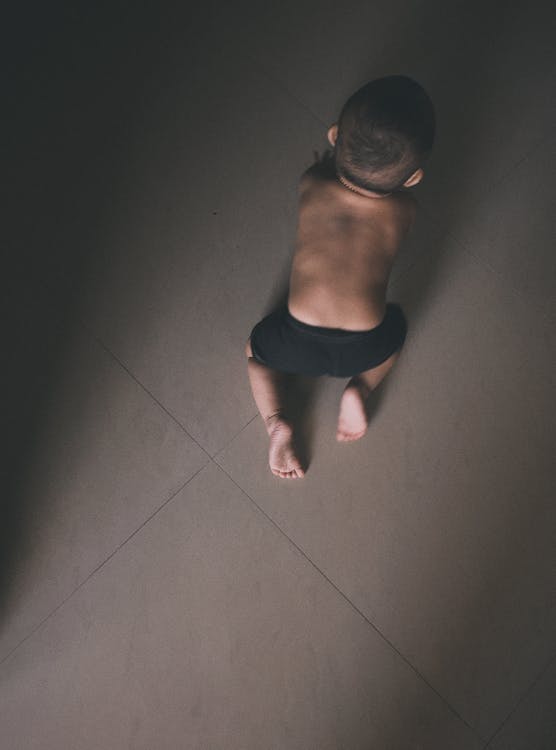 Toddler in Black Shorts Crawling on Grey Floor Tiles