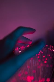 A mesmerizing image of a hand touching glowing neon pink fiber optic lights, creating a magical atmosphere.