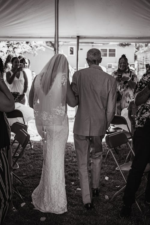 Grayscale Photo of a Bride and Her Father Walking Together