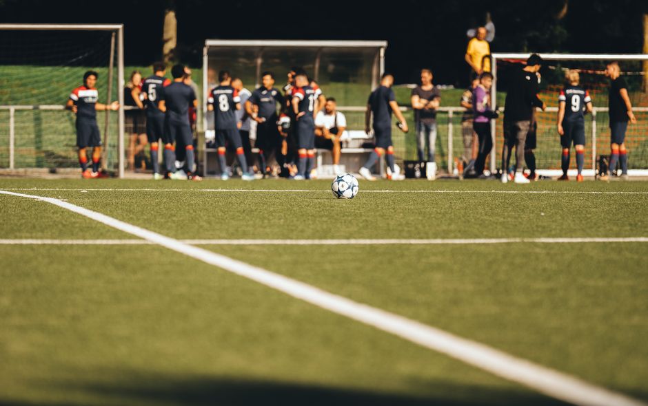 Soccer teams lined up on a floodlit pitch