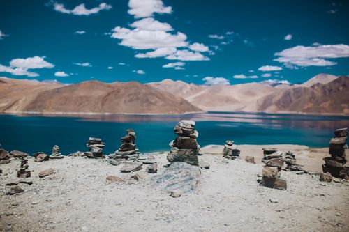 Free Tranquil scene of rock stacks by a clear mountain lake under a blue sky. Stock Photo