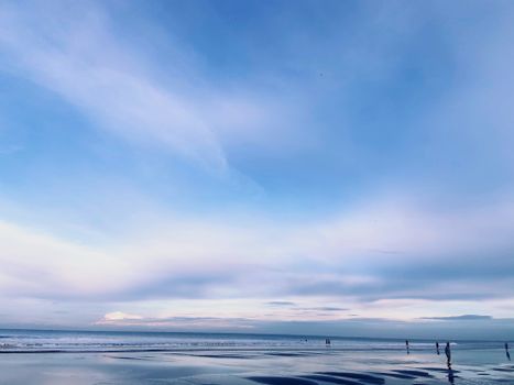 Serene beach view with a vast blue sky reflecting on calm waters, perfect for relaxation.