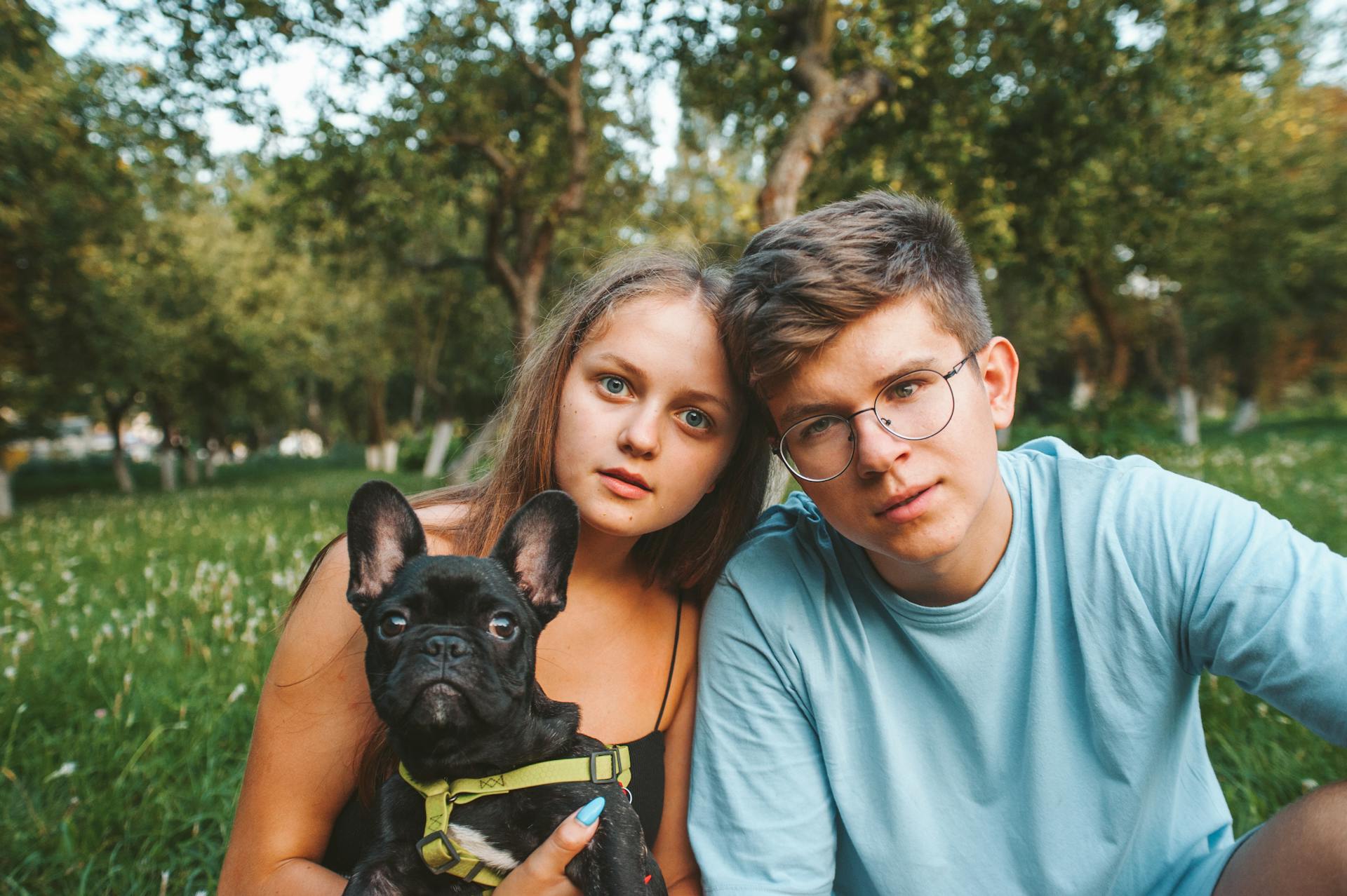 A Girl and a Boy Posing with a Pet French Bulldog