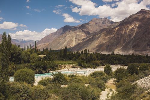 Free Stunning view of mountains, river, and lush forest under a clear blue sky. Stock Photo