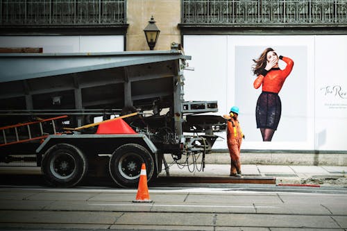 Man in Orange Safety Suit Standing Beside Truck Bed