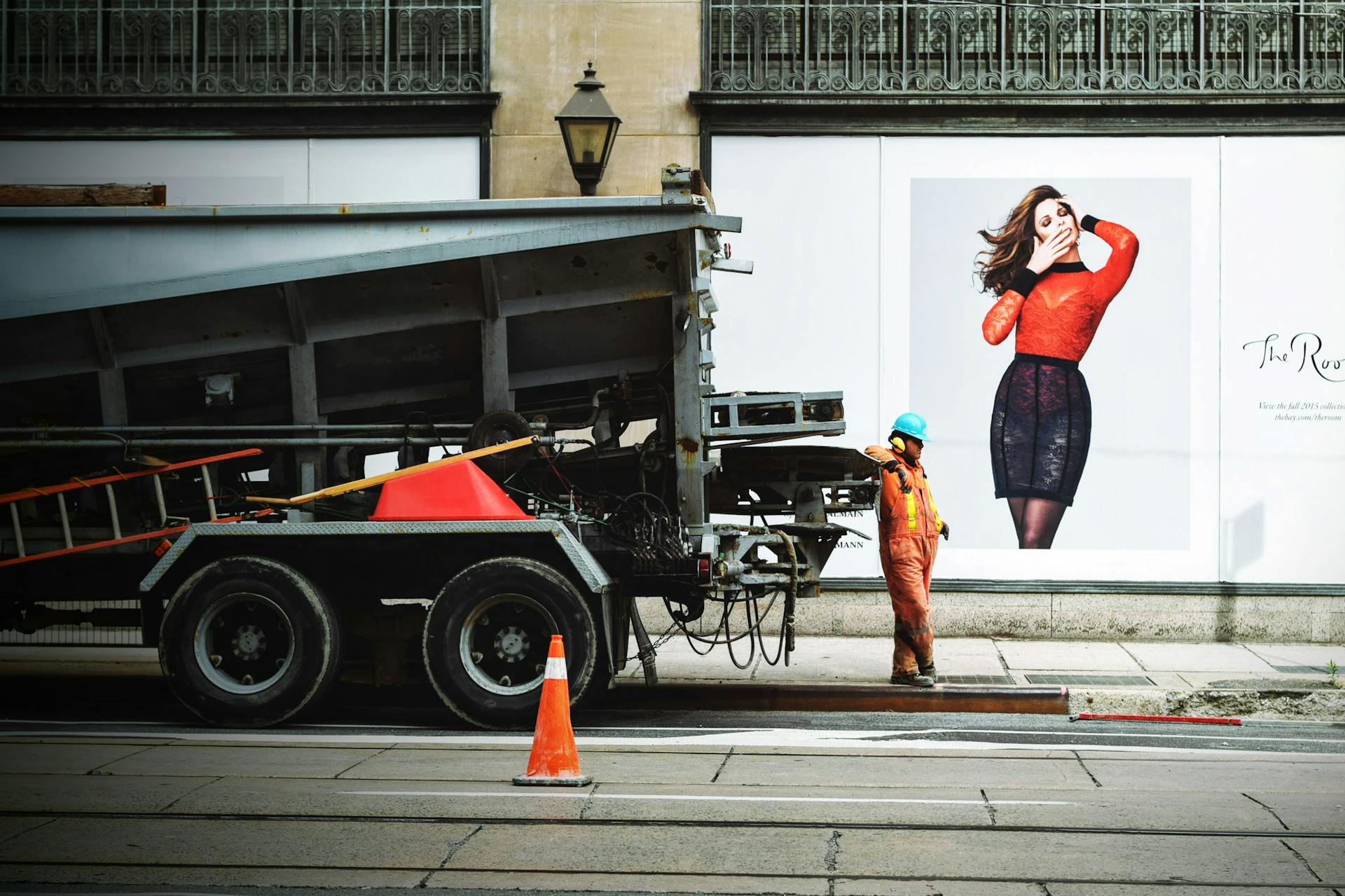 A construction worker operates beside a truck on a city street.