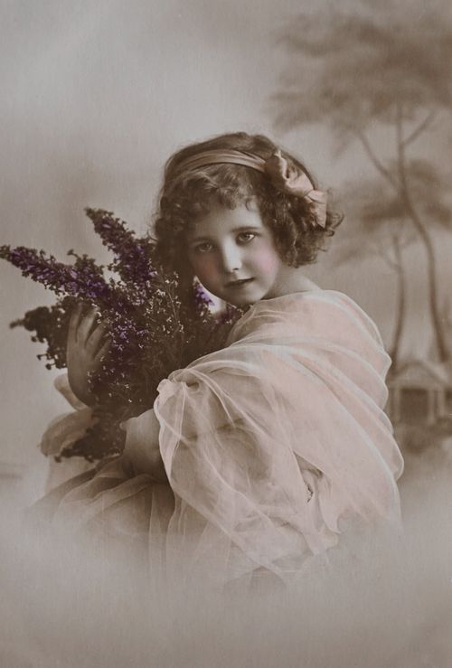 Free Sepia-toned vintage photo of a young girl holding a lavender bouquet, evoking nostalgic charm. Stock Photo