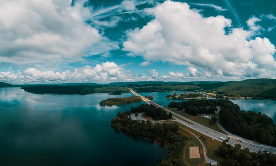 Aerial shot of a bridge crossing a serene lake with surrounding forested landscape in Jasper, Tennessee.