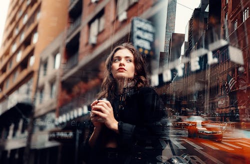 A Double Exposure Photography of a Woman in Black Long Sleeve and a City