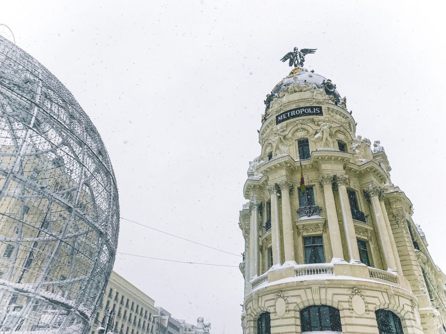 Toma en ángulo bajo del Edificio Metropolis en Madrid durante un día de invierno nevado.