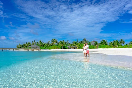 Free A Couple Standing on the Beach Stock Photo