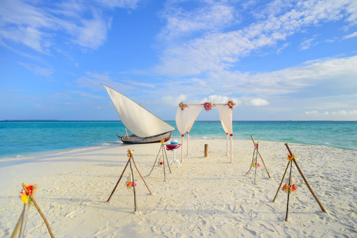 Romantic beach wedding setup with a sailboat in the background