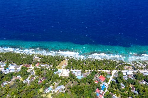 Free Stunning aerial view of Fuvahmulah Island's turquoise coastline and vibrant town in the Maldives. Stock Photo