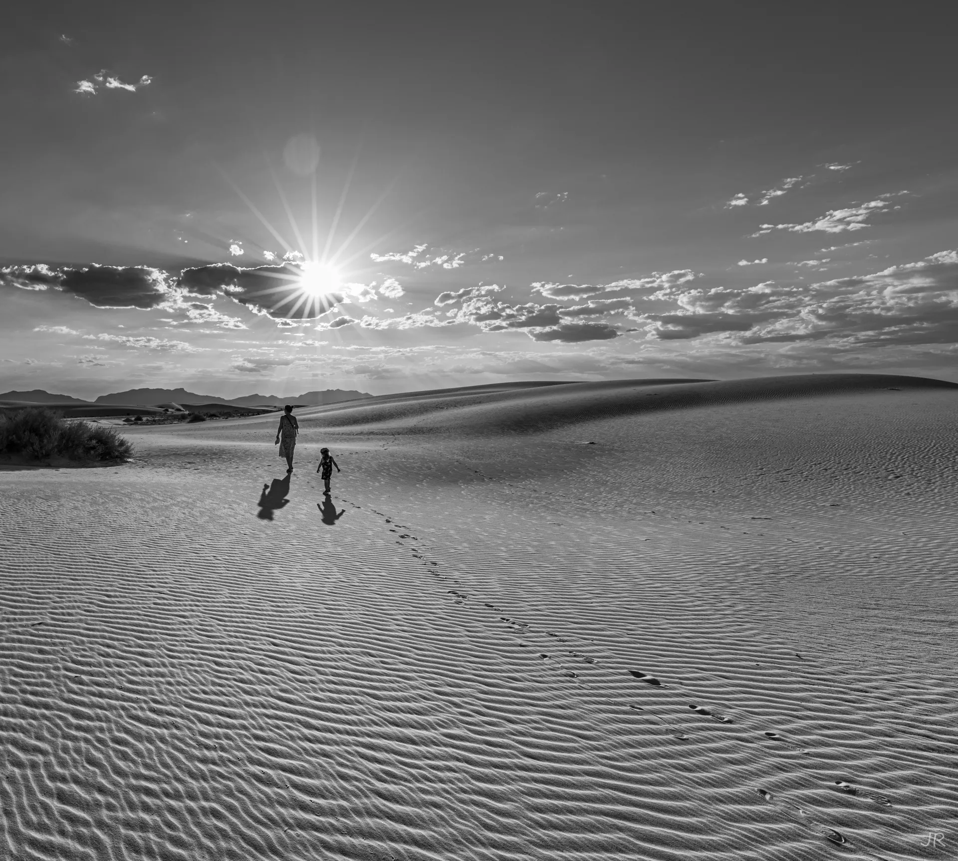 Silhouettes walking across White Sands desert at sunset, with shadows and sun flares. Silhouettes walking across White Sands desert at sunset, with shadows and sun flares.