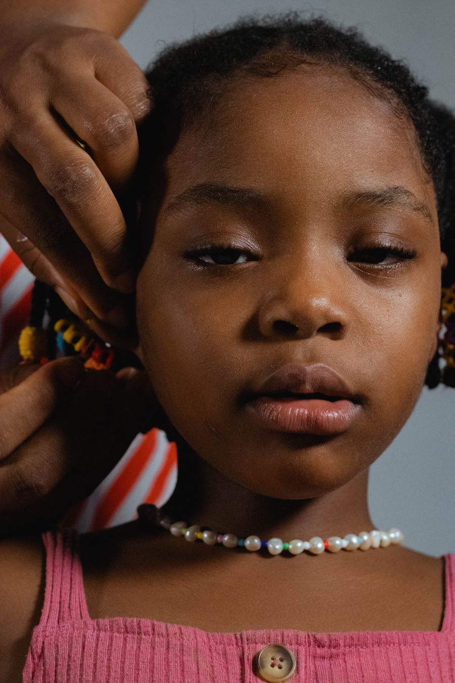 Young girl with neatly braided hair being styled with careful sectioning and decorative detail