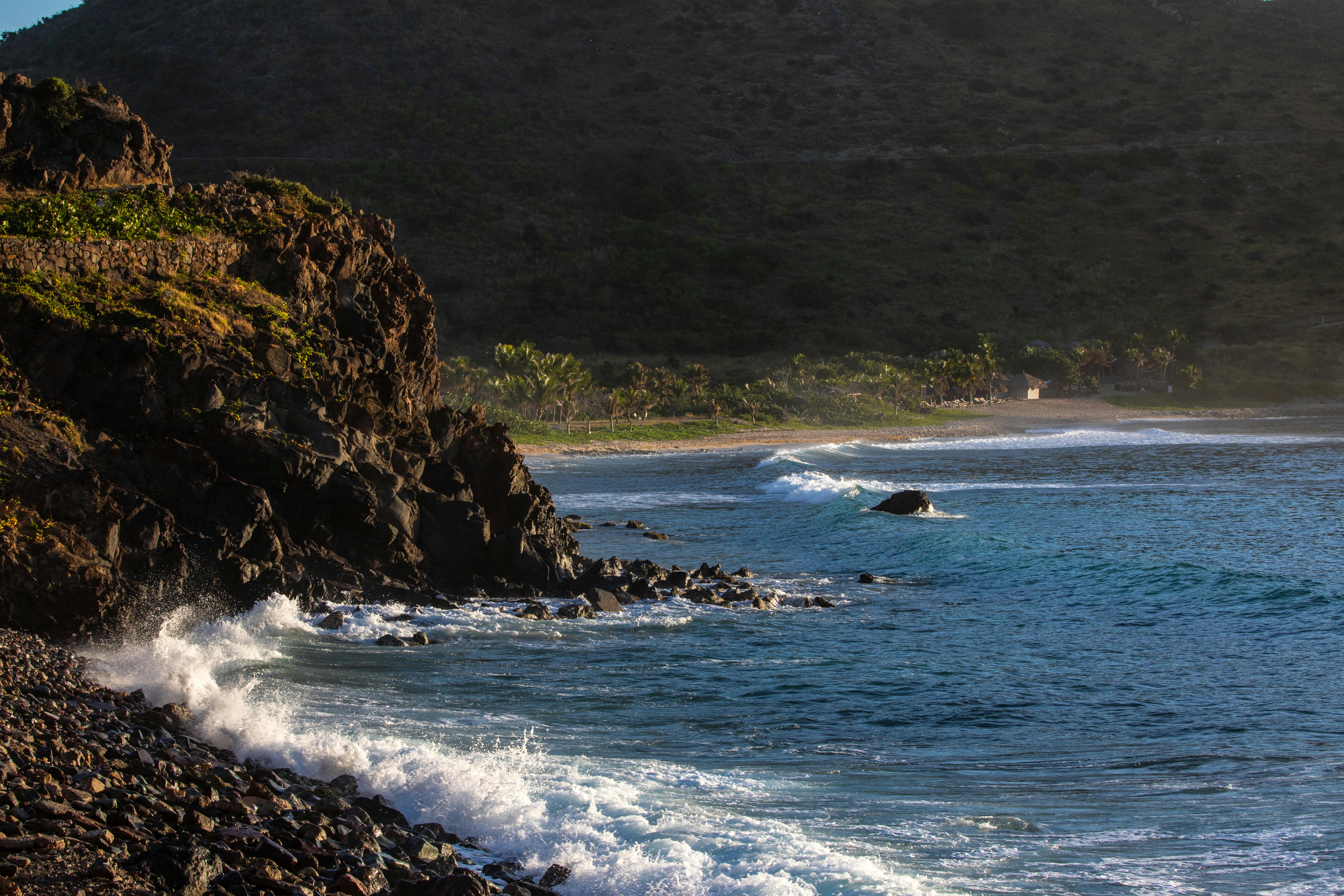 Captivating coastal view with waves crashing against rocky cliffs under a sunset sky.