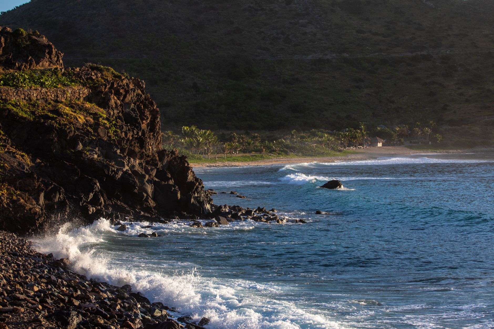 Captivating coastal view with waves crashing against rocky cliffs under a sunset sky.