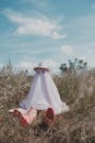 Woman in White Dress and Pink Hat Standing on Brown Grass Field