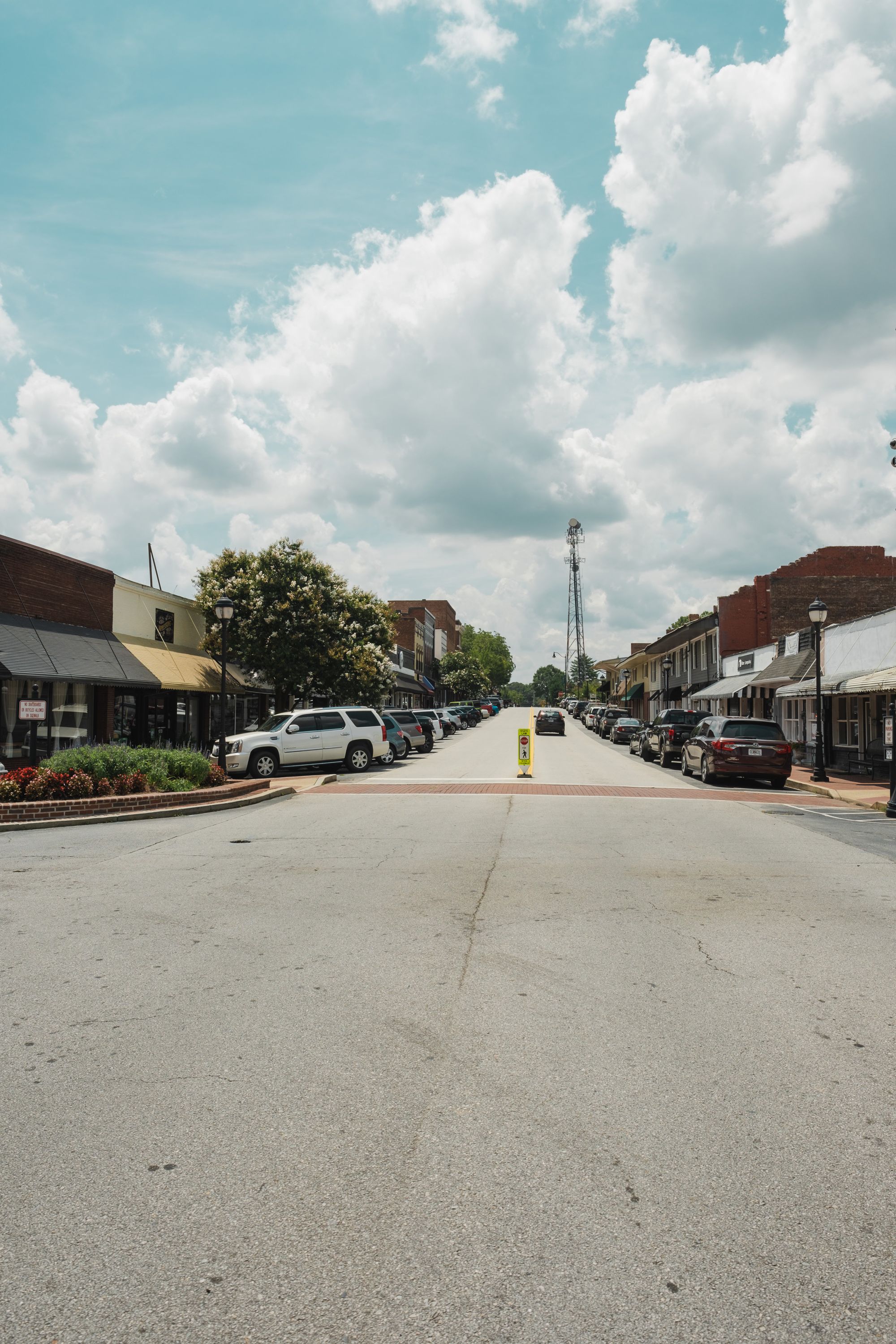 A sunny downtown street lined with historic brick storefronts