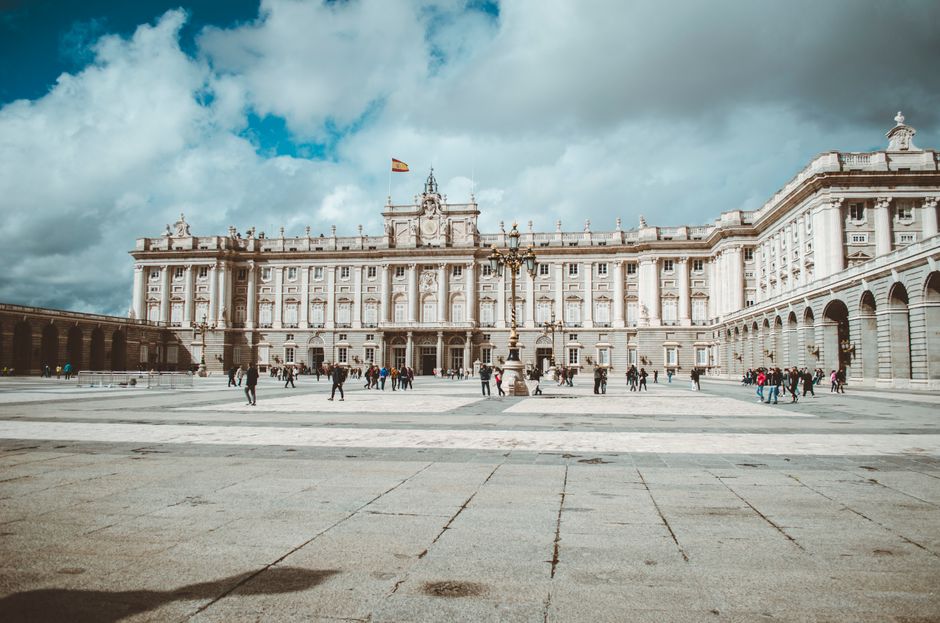 El majestuoso Palacio Real de Madrid con turistas disfrutando de un día nublado pero hermoso.