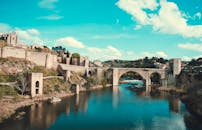 在明亮的天空下，西班牙托莱多罗马桥的风景倒映在平静的河流上