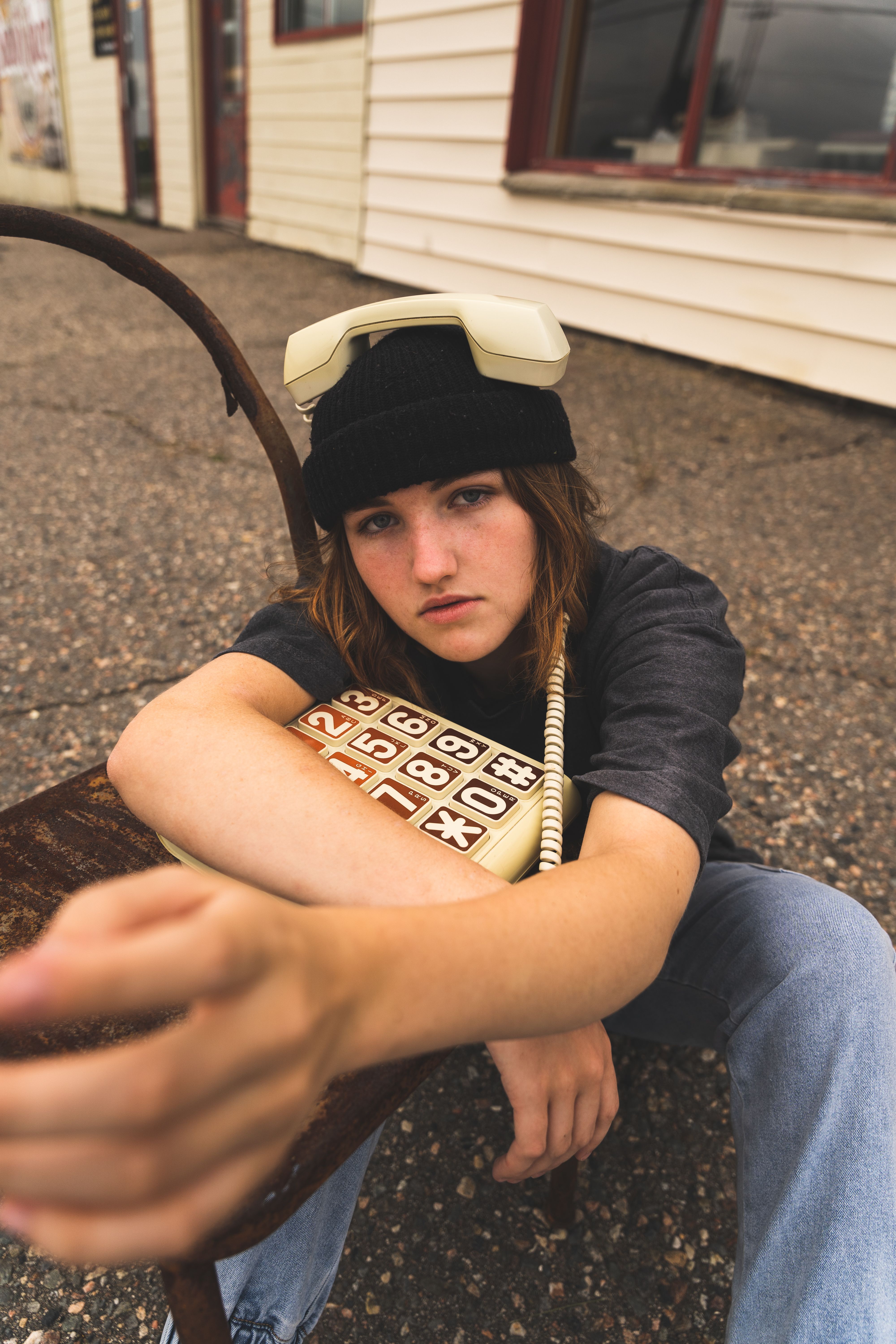 Young person in beanie with retro phone outdoors, showing vintage style.